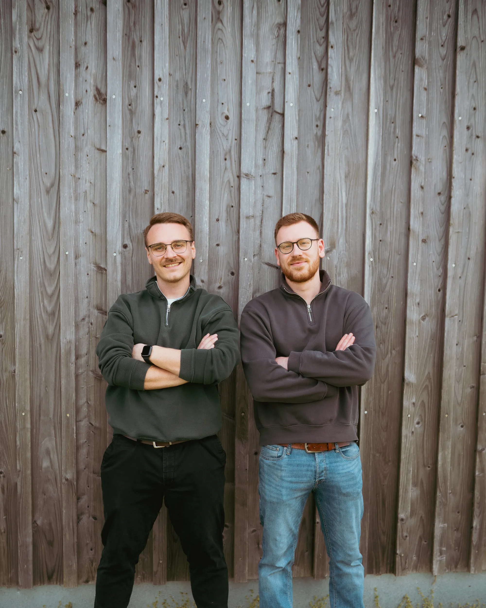 Ferdi und Dani vor einer Holzwand, Hintergrund